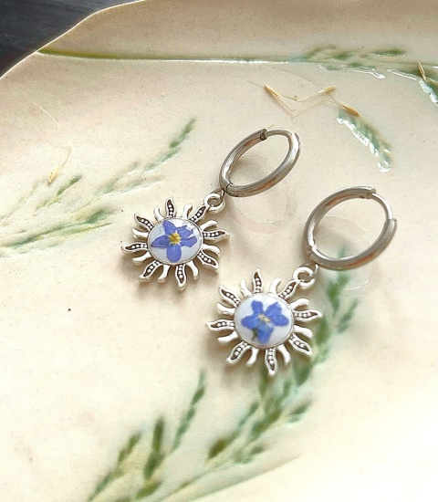 Posrebrzane kolczyki koła z zawieszkami w kształcie słońca i prawdziwymi niezapominajkami w żywicy.