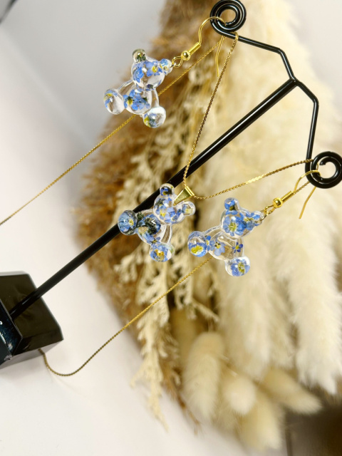 Zestaw biżuterii handmade z żywicy epoksydowej – kolczyki i naszyjnik z zawieszkami w kształcie misiów, z zatopionymi niezapominajkami i złotym wykończeniem ze stali chirurgicznej Zestaw biżuterii handmade z żywicy epoksydowej – kolczyki i naszyjnik z zawieszkami w kształcie misiów, z zatopionymi niezapominajkami i złotym wykończeniem ze stali chirurgicznej