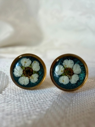 Kolczyki wkrętki z tawułą – biżuteria handmade na tle butelkowej zieleni