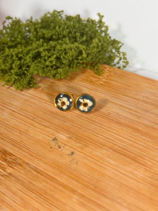 Kolczyki wkrętki z tawułą – biżuteria handmade na tle butelkowej zieleni